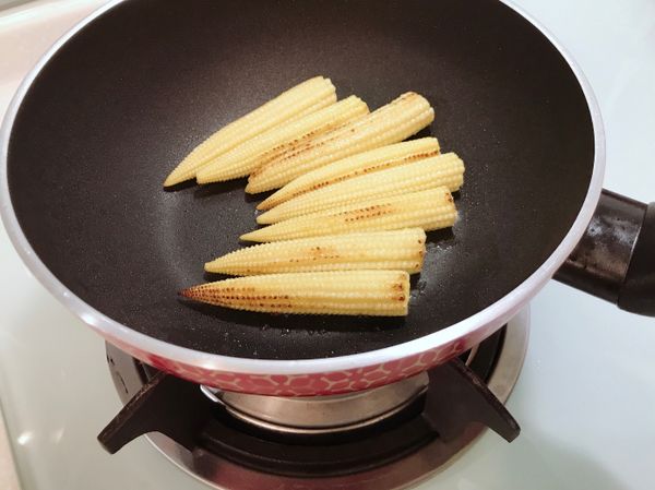 鍋中倒入量稍微多一點點的沙拉油，中火翻煎玉米筍至表面有點焦褐色。