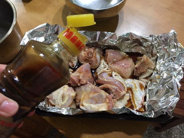 烤盤上鋪鋁箔紙（四周鋁箔要有些高度，因為麻油易噴濺，且方便等一下加蓋另一張鋁箔紙於其上），將薑片鋪底，並將醃好的雞肉放入烤盤，再將袋中麻油平均淋在每塊雞肉上頭，並可視情況再多淋些麻油。