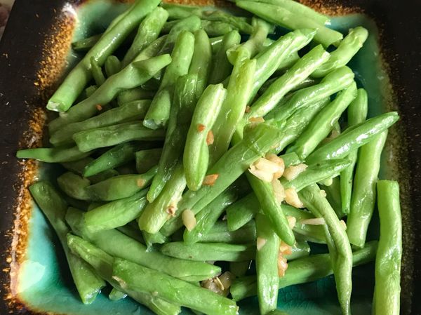 四季豆用手剝去粗撕（+1匙小蘇打流動水去除農藥）蒜頭拍碎切末，熱油鍋加半匙鹽下四季豆炒軟即可盛盤！