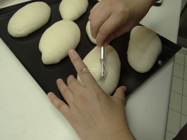 身體跟麵包平行，割線先劃一刀直線(邱智偉老師割線刀片使用口訣：1.平放(身體亦與麵團平行)→2.轉向前方90度→3.提起來45度→4.往身體方向傾斜45度，僅把麵團表皮挑起即可。)