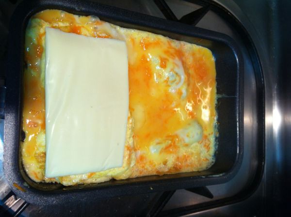 將蛋打散,放入煎蛋器中,再放進一整片的芝司樂起司,蛋熟後捲成蛋捲