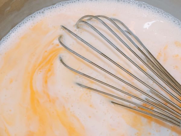 手模牛奶不燙就可以將蛋液倒入一起拌勻，過篩兩次後倒入塔皮