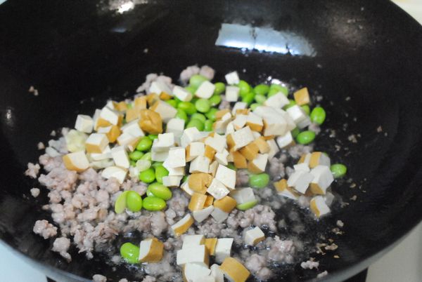加入蒜頭,豆干和毛豆拌炒.