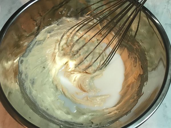 再分次加入鮮奶攪打，這步驟會比較難攪打均勻，請少量少量加入鮮奶打勻，讓奶油糊能吃進鮮奶。