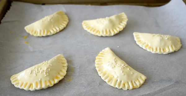 將酥皮對摺，用叉壓實封口，再在酥皮上面塗一層蛋液，灑上白芝麻