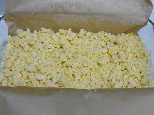 水果從冰箱取出後倒掉滲出的湯汁，再加一匙玉米粉拌勻，輕輕均勻的放麵糊上層。上層撒奶酥。※烤盤先放一張烘培紙，並預留長度，烤好可方便提出來切片。※