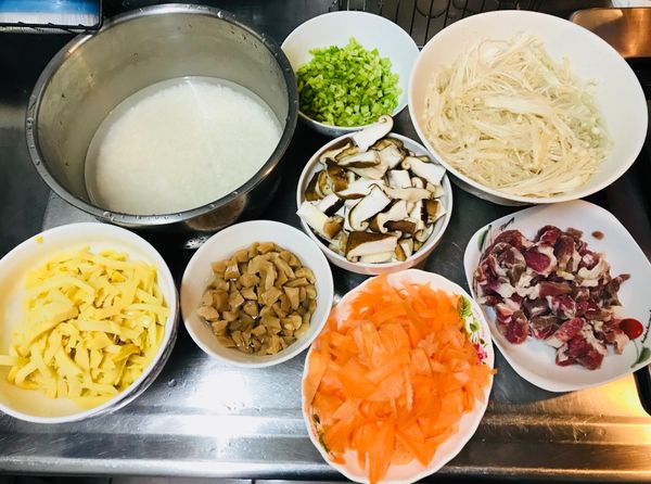 白米洗乾淨泡水30分鐘。
紅蘿蔔用削皮刀削成薄片。
梅花肉切條。芹菜切丁。
香菇切條。菜餔切丁洗淨去鹹。
（金針菇沒用到，請忽略）