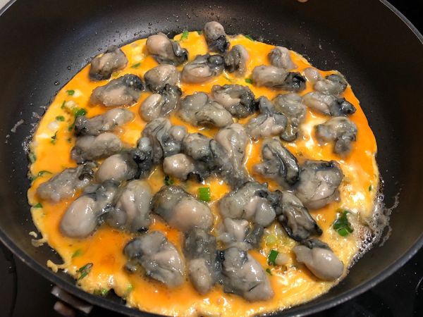 起油鍋，爆香薑末、蔥花，蛋液裡加1匙鹽拌勻後，倒入鍋中，再將燙過的鮮蚵均勻的放入鍋內，讓每顆蚵仔都能沾到蛋液。蓋上鍋蓋小火悶熟（約1分鐘）。