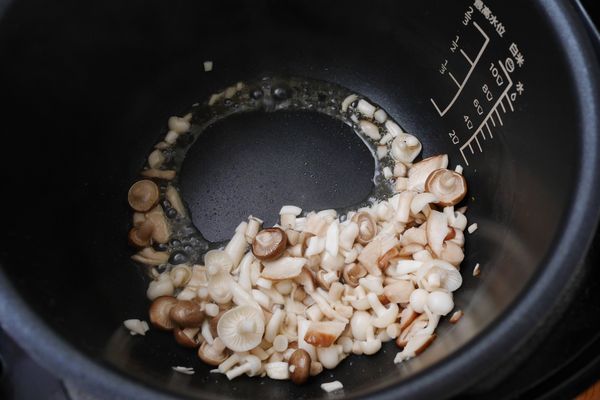 選擇「烤雞」模式按「開始烹飪」，內鍋加熱後倒1/2茶匙油，油熱倒入綜合菇，慢慢拌炒先讓綜合菇釋出水份。