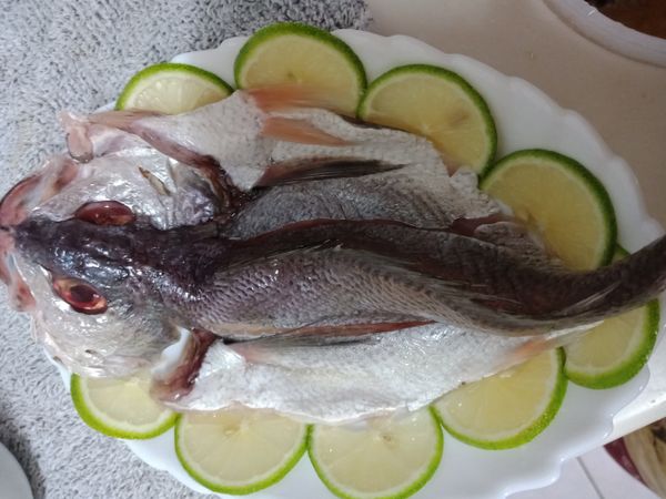 魚先用刀子從魚腹部剖開切成两片，不要剖段然後洗淨用一點米酒及鹽醃—下去腥味，蒜切末，蔥切末，香菜切碎，辣椒切末，檸檬半顆切成溥片，半顆擠汁