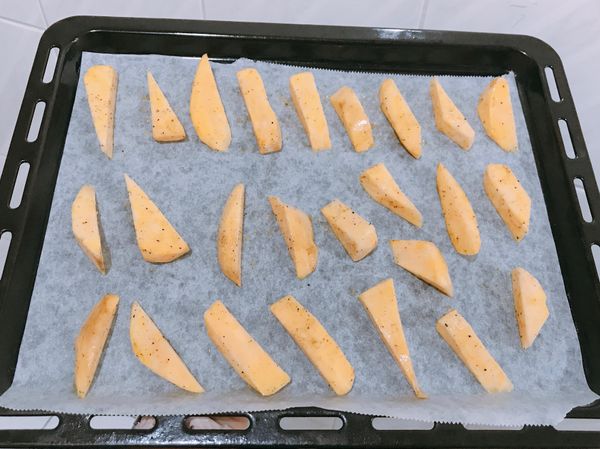 地瓜🍠洗淨去皮（也可不去皮）看個人喜好，紙巾吸乾多餘水分，放入鍋子均勻灑上蒜粉、黑胡椒，用湯匙或乾淨的手混合讓地瓜均勻裹上調味料，依續擺在烤盤上