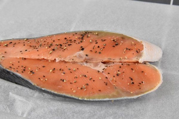 將薄鹽鮭魚放在烘焙紙上，抹滿黑胡椒粒提香
（我是買已經處理好的薄鹽鮭魚片，所以它本身就有鹹度不需要自己做太多的加工）