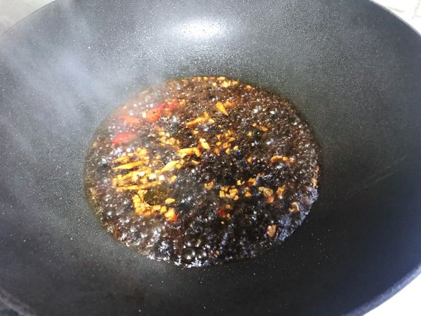 爆香蒜末後加入醬汁、薑絲和辣香，煮滾後放蝦子。