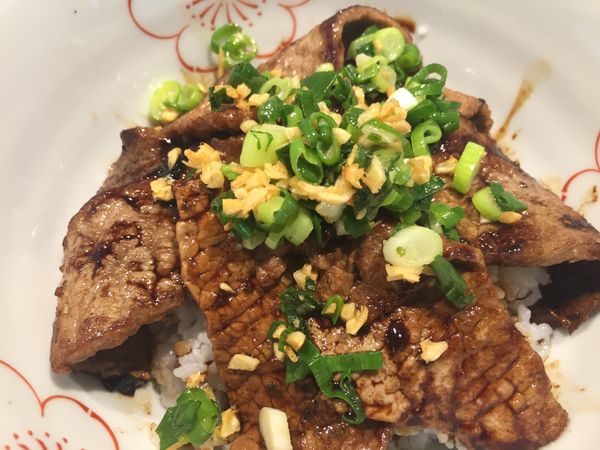 把白飯盛入碗中，再把牛肉逐塊鋪上，淋上日式醬油，再加上蔥蒜即成。