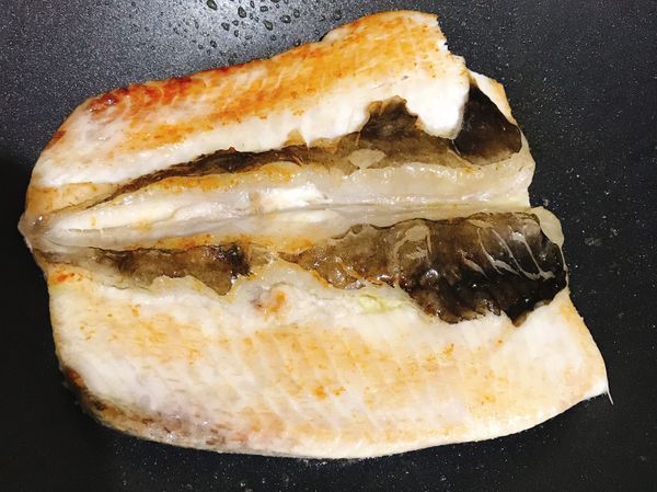 開蓋後壓一下魚肚讓一些油脂跑出來，接著翻面蓋上鍋蓋繼續悶煎5-8分鐘