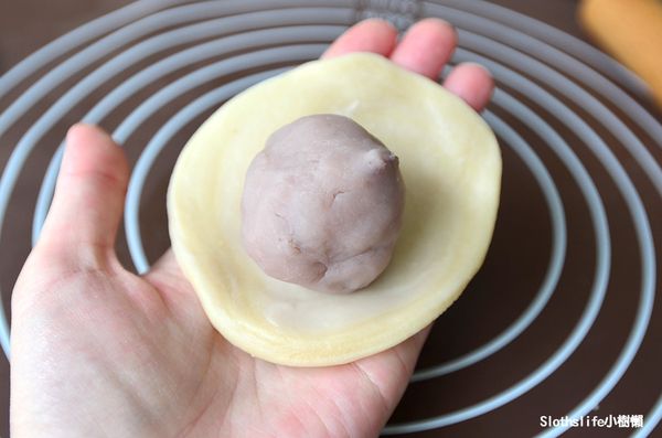 先稍微用手掌壓平後，再使用擀麵棍將周圍捍出約2公分後，放入芋泥球，餅皮往內收口捏緊，注意不要壓到紋路。