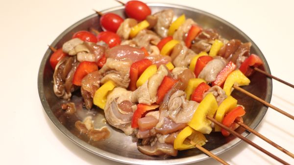 用竹籤將彩椒與雞肉間隔的方式串起來，頂端插入小番茄