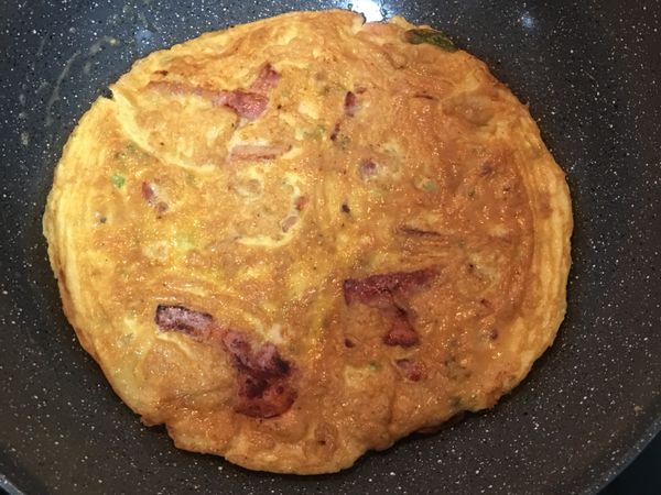 開鍋、翻面續煎到另一面也上色即可。
不會甩鍋翻蛋也沒問題，可以先準備個大盤子，把底下已煎好的蛋，翻到大盤子上，接著再滑回原鍋中，煎到底部也金黃後，最後滑回大盤子裡，便完成了培根蕃茄蛋囉～