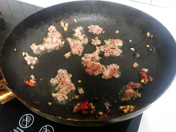 爆香花椒、蒜末、薑末、辣椒，然後加入絞肉快炒。