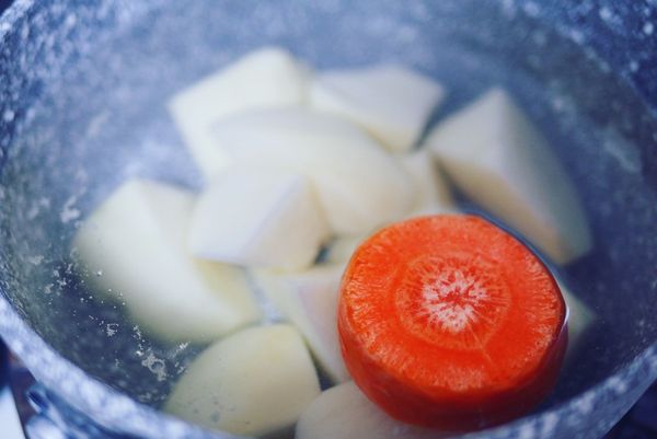 水煮馬鈴薯、紅蘿蔔：馬鈴薯洗淨、削除外皮，切成 4-5 公分大小的塊狀；取一個小鍋，注入冷 水，並加入馬鈴薯塊以及五分之一節的紅蘿蔔，水滾後小火續煮 20 分鐘。