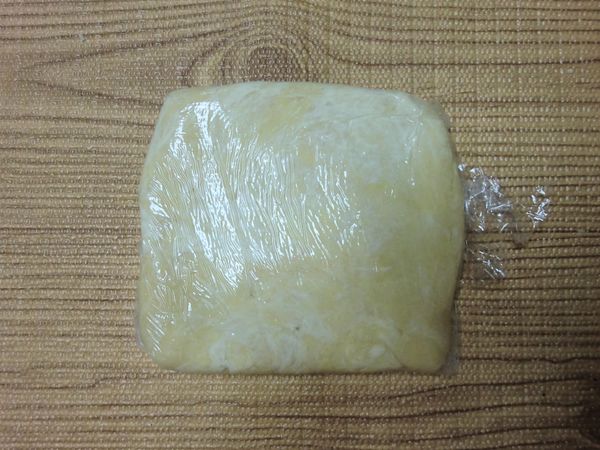 把麵糰置於保鮮膜上，利用保鮮膜把麵糰壓整成扁平狀，包好放入冰箱冷藏 30 鐘。