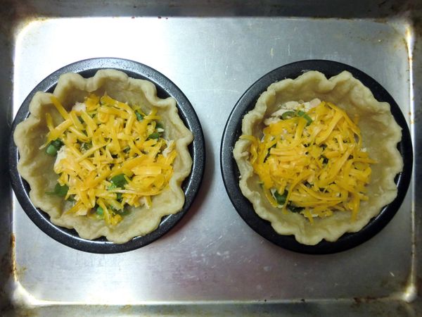 在預烤 10 分鐘的派皮中放入鮪魚、起司及蔥花，再撒上適量現磨黑胡椒。