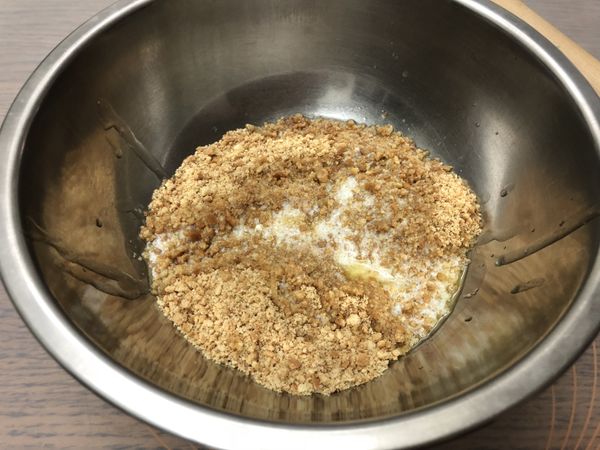 加入融化的無鹽奶油，以橡皮刮刀或湯匙將餅乾碎和奶油混合均勻。