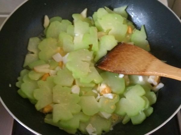 大概三分鐘左右，佛手瓜稍微變色軟化，開蓋加入鹹蛋米酒胡椒粉拌炒，中火炒至收汁