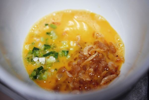 加入材料：取一個中型碗 (飯碗怕太小)，打一顆蛋，並打散。加上炒好的蝦皮、蘿蔔乾；接著再加糯米醋、醬油，跟一小匙白芝麻油。