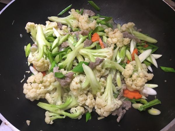待白花椰菜熟後，打開鍋蓋，加入蒜苗炒勻即可起鍋。
