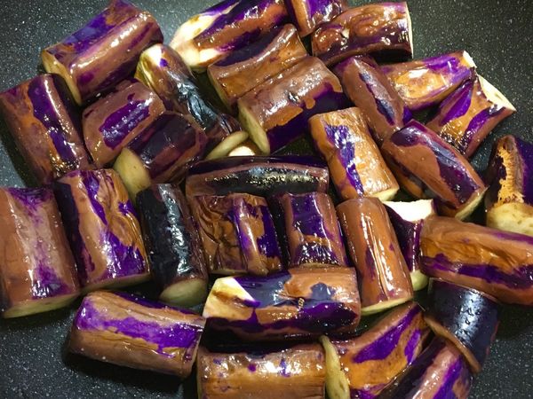 油鍋加熱放入茄子後快速攪拌，讓每段茄子都沾到油，均勻灑上鹽巴後再次拌勻⋯