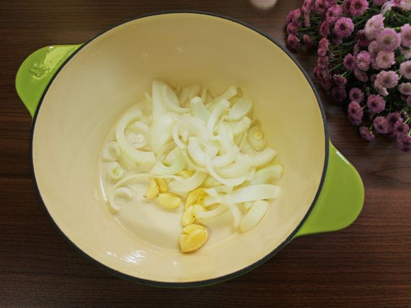 取一燉鍋, 加入一大匙油, 洋蔥、蒜頭, 中火炒至洋蔥均勻吸附油末