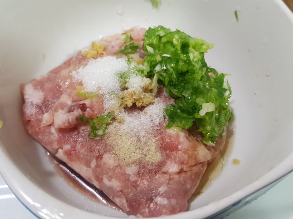 絞肉加入1/3紅匙鹽巴，少許胡椒粉和五香粉（撒2到3下），1匙糖，1大匙醬油，薑泥，蔥末，1匙香油，米酒，充分攪拌均勻，大略分成10份備用。