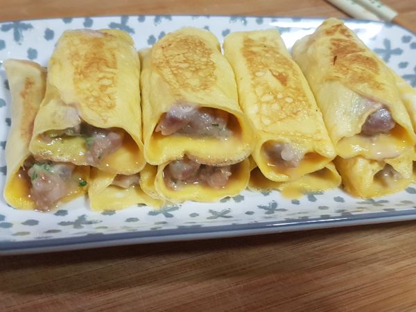 此份量約可做十個。肉餡未熟，只是蛋捲皮熟，將煎烤好的蛋捲餃放在盤子上。