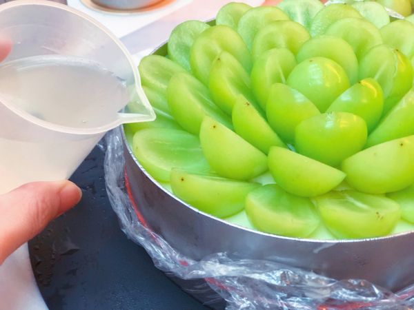 果凍液確實放涼了之後，倒入排滿葡萄的幕斯框的最上層。再送回冰箱冷藏至完成凝固。