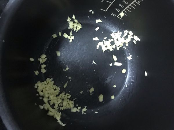 萬用鍋點選「烤雞」模式，放入麻油及蒜頭爆香