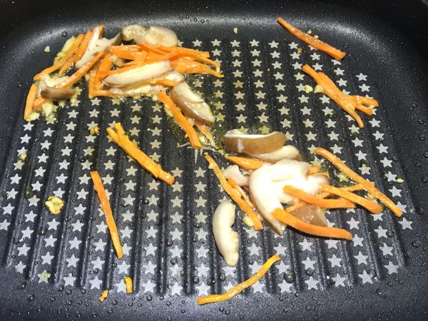 大蒜拍扁切碎，下油鍋。放入紅蘿蔔絲跟香菇片。拌炒