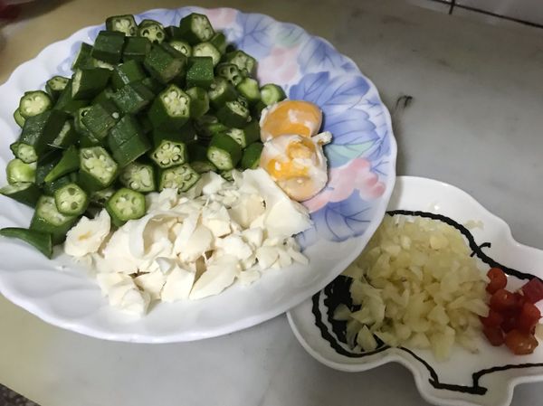 秋葵用鹽巴洗淨，切成小塊狀，鹹蛋去殼，蛋白蛋黃分開，蒜頭切成蒜末，辣椒切段。