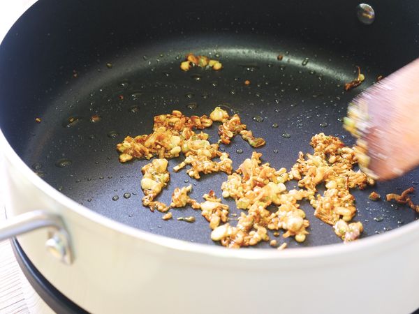 將鍋子洗淨後放回爐上，轉至煎炒模式，火力設置在60檔，倒入食用油和紅蔥碎小火慢炸，當紅蔥轉金黃後便可撈起（紅蔥焦掉會轉苦，一變色後就可以撈起了）