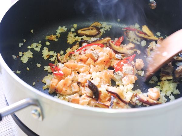 同鍋內下蒜末、辣椒、洋蔥末以及香菇，接著放入鮭魚炒香