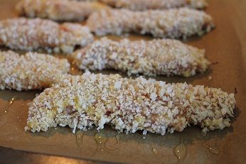 裹好粉的雞柳平放在鋪好烘培紙的烤盤上, 用小湯匙在表面淋上少許的油