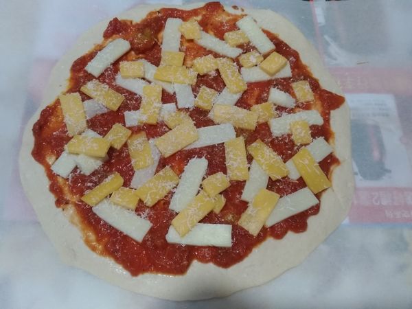 把蕃茄罐頭上平底鍋加入鹽，胡椒，義大利香料炒製後均勻抹上餅皮，再鋪上起司及現刨帕瑪森。