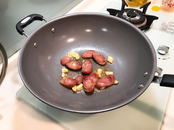 倒油、加鹽，爆香蒜頭、香腸。