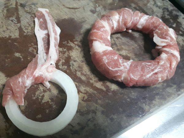 將肉片慢慢捲上洋蔥圈的表面