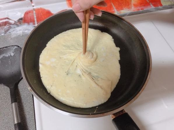 禮服蛋包成型後，不要移開筷子，一隻手握住鍋柄迅速起鍋，從鍋內將禮服蛋包輕輕鋪蓋在飯包上面。