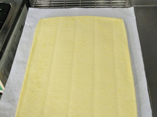 出爐重敲一次，蛋糕放到烤網上撕掉邊邊的紙放涼，放涼後表面上放一張烘焙紙，拉起邊邊翻面撕紙