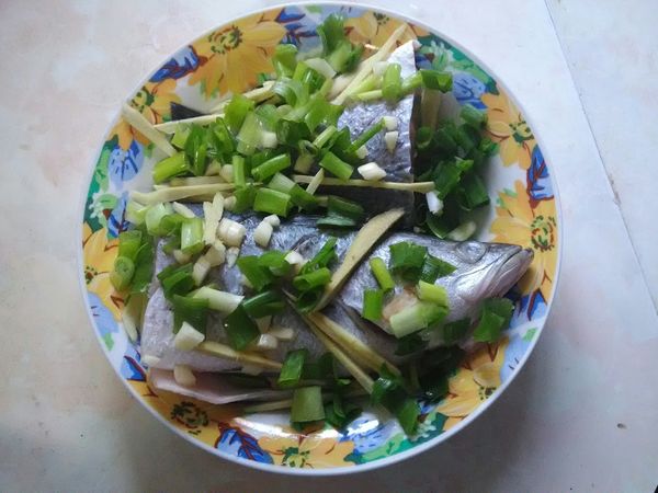 金目鱸魚清洗，刮鱗，切兩段，在盤上放入鱸魚，蔥末，薑絲，蒜末，加入米酒適量，放入電鍋蒸