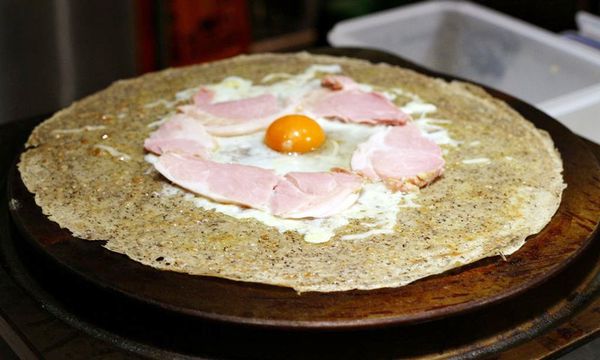 薄饼成形后边边会翘起，然后翻面，煎至两面熟透，放入炒好的洋葱、培根，中间打一颗蛋后撒上芝士；