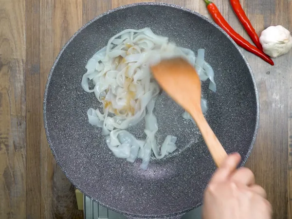 鍋中下油，倒入河粉、醬油、老抽，快炒至均勻上色，先把河粉取出至碗中。