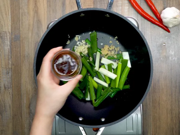 換一個鍋子，下油，放入蔥段、薑末、蒜末、沙茶，拌炒均勻。